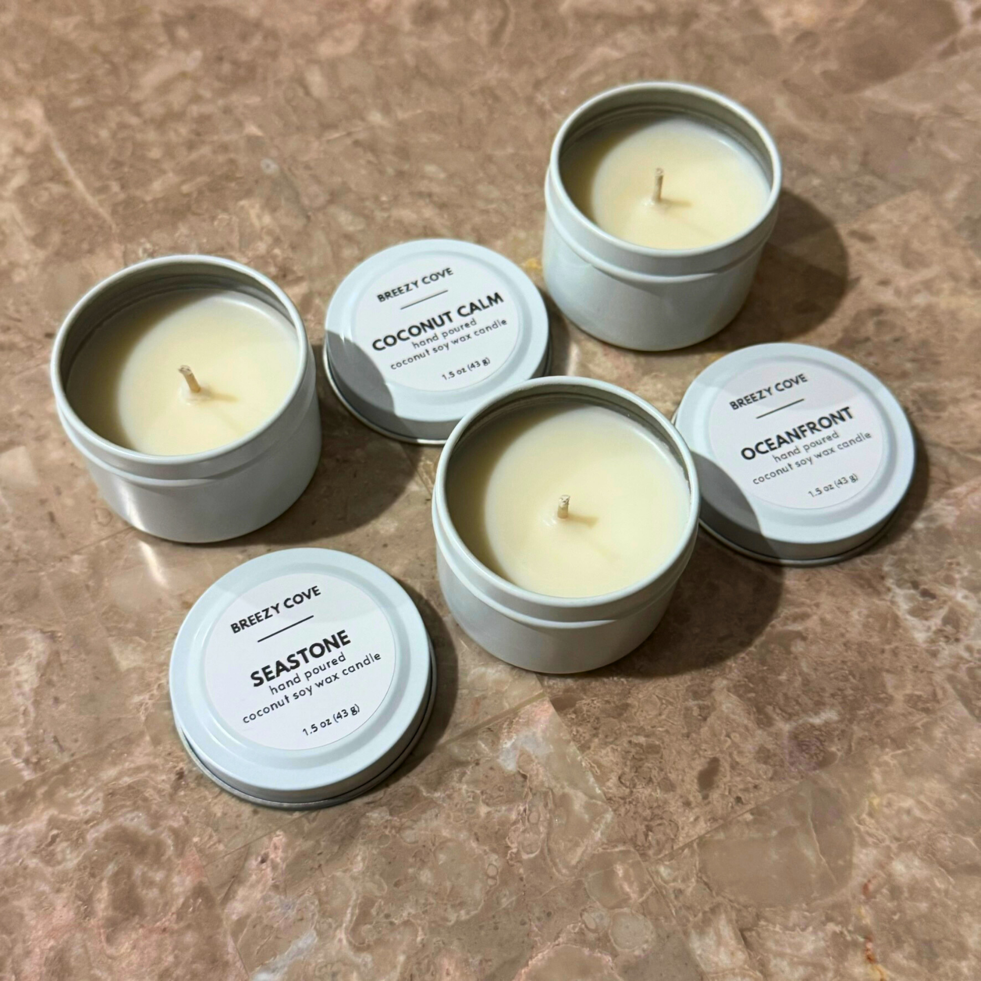 Open nontoxic long-burning beach candles in white tins shown with lids off.