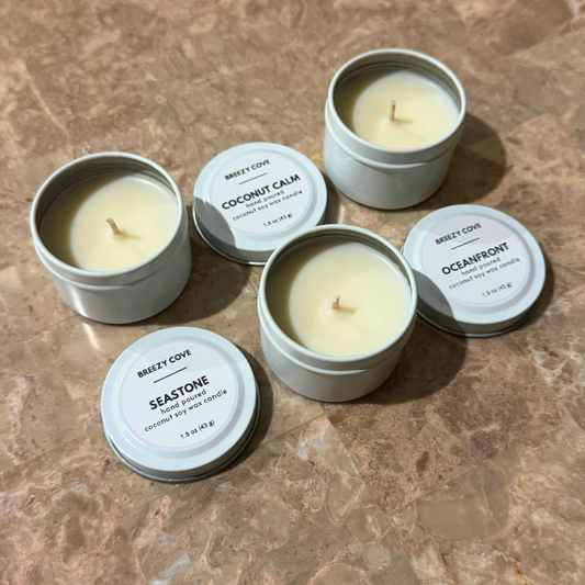 Open nontoxic long-burning beach candles in white tins shown with lids off.