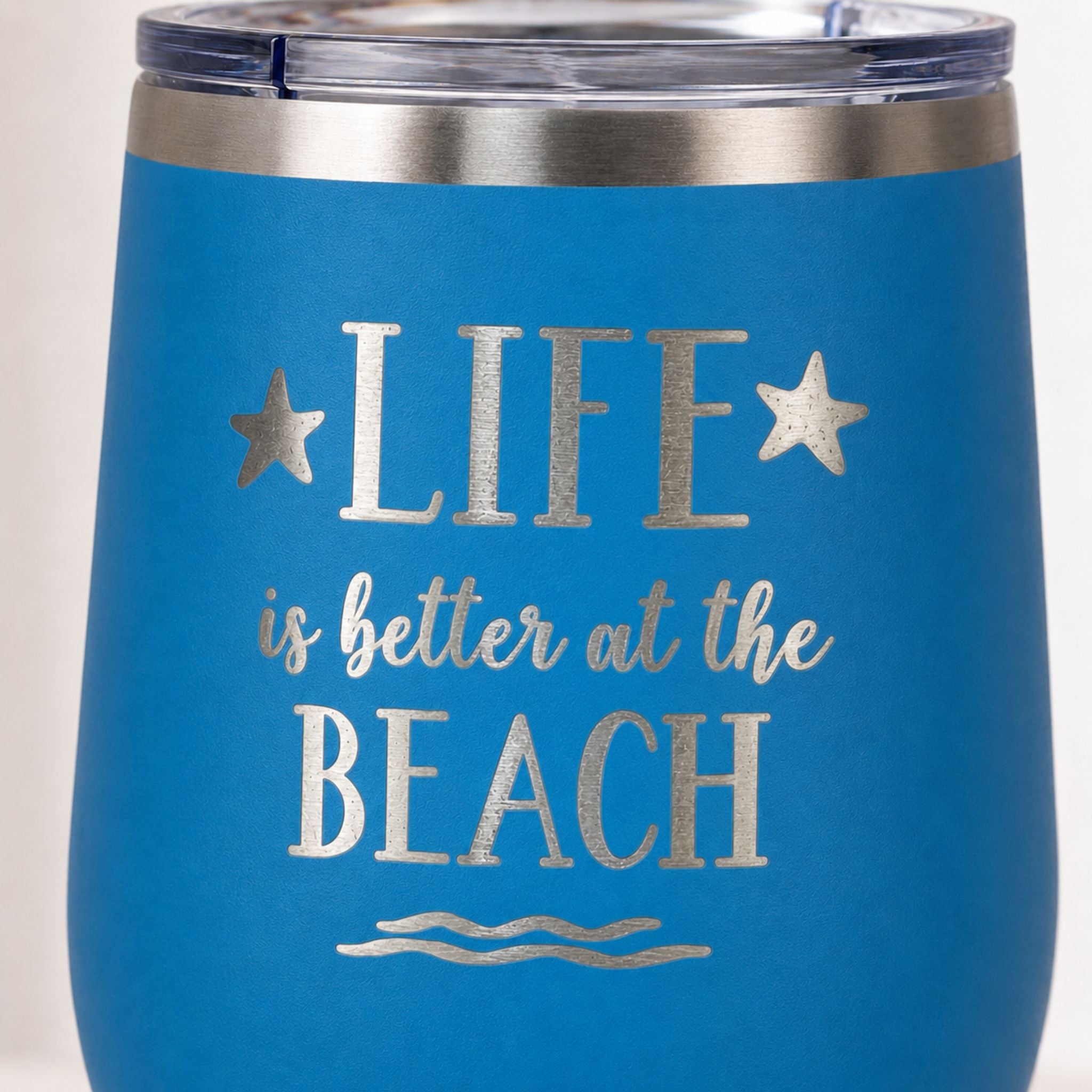Close-up of ocean blue beach tumbler with Life is Better at the Beach design
