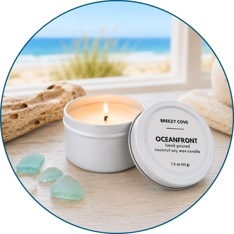 Lit Oceanfront beach candle in a coastal setting with sea glass, driftwood, and an ocean view.