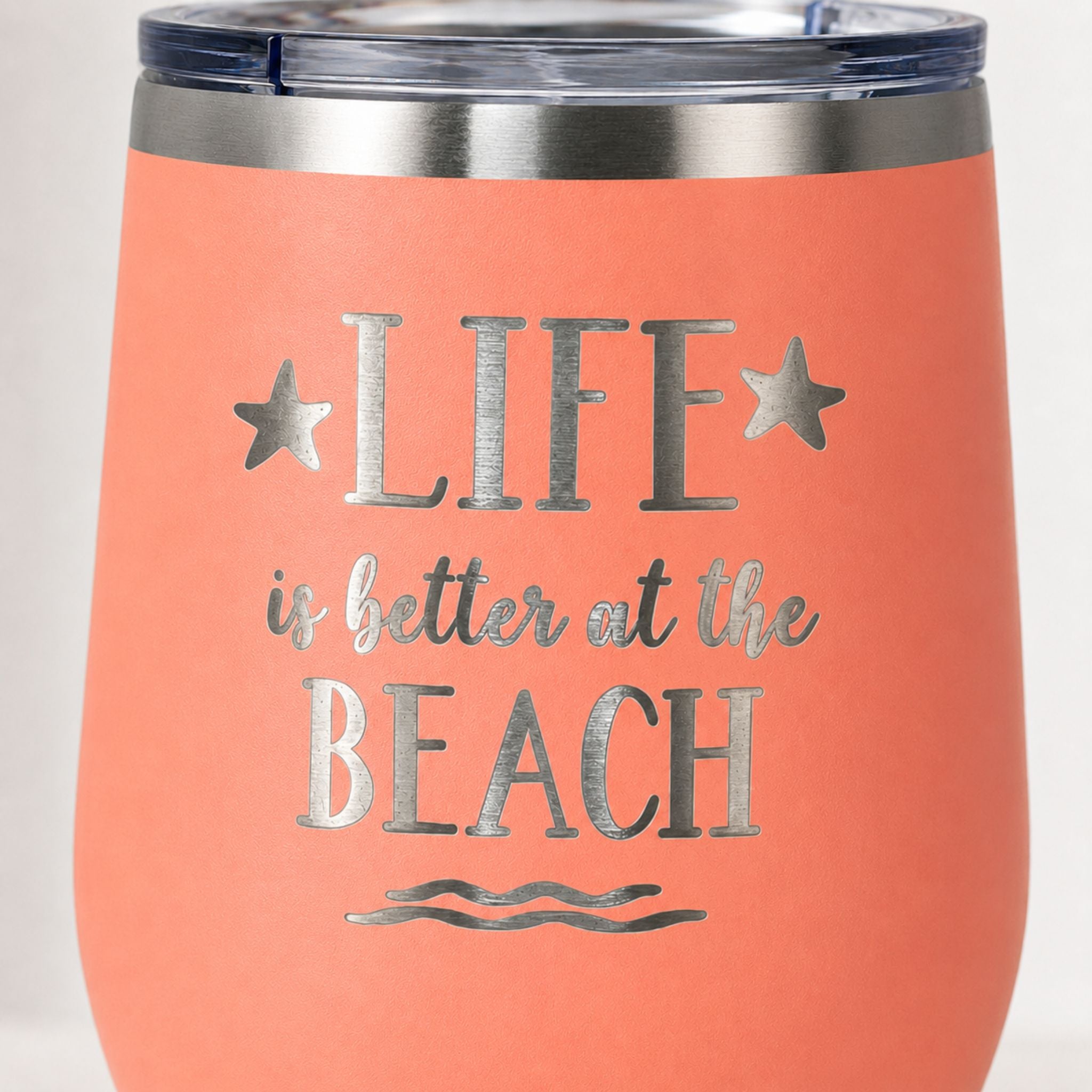 Close-up of peach beach tumbler with Life is Better at the Beach design