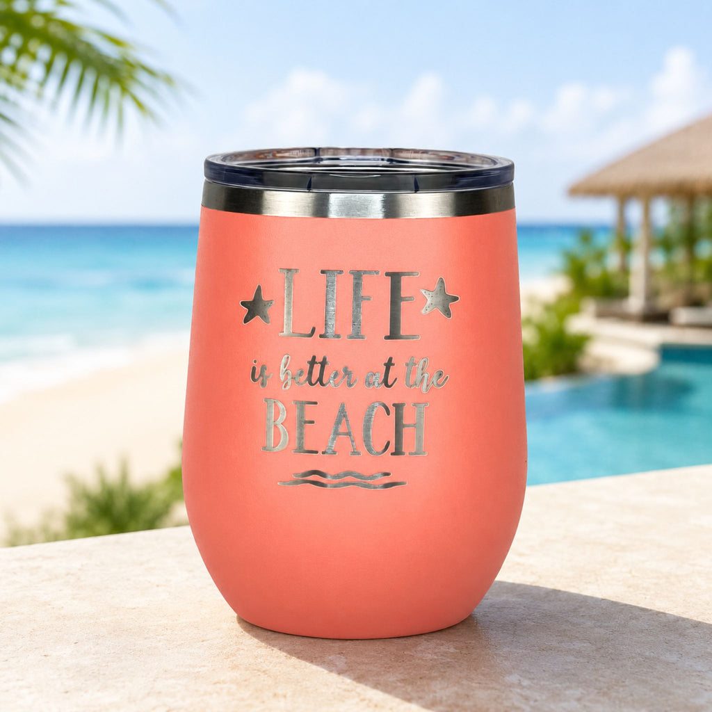 peach metal tumbler with 'Life is better at the Beach' text by a poolside with palm trees and an ocean view as a beach gift for women