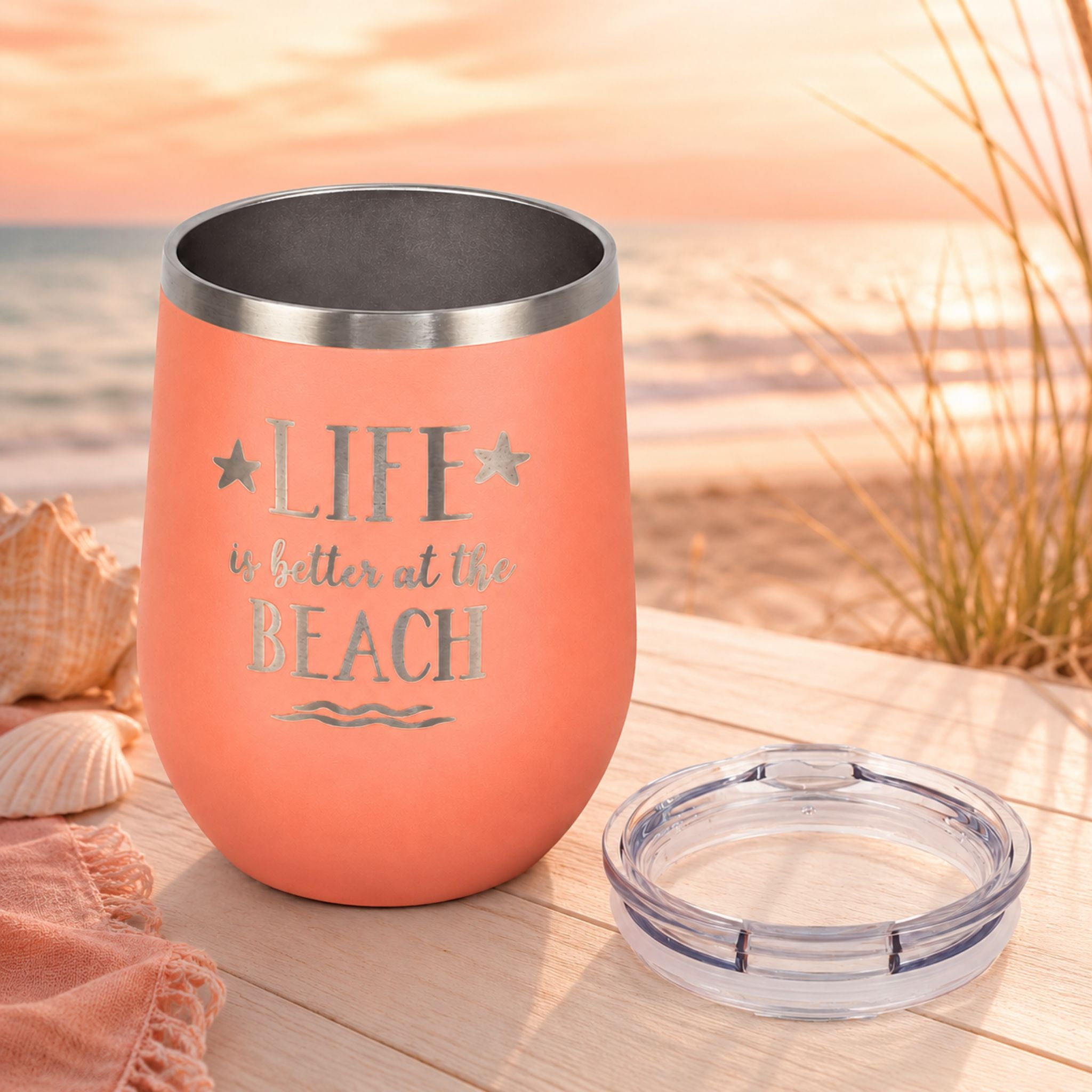 Peach wine tumbler with clear lid shown beside the cup in a beach-inspired setting