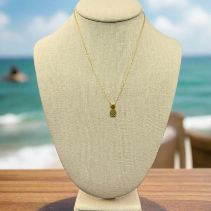 pineapple pendant necklace 18k gold dipped necklace is perfect jewelry accessory for beach lovers on linen jewelry display with ocean background