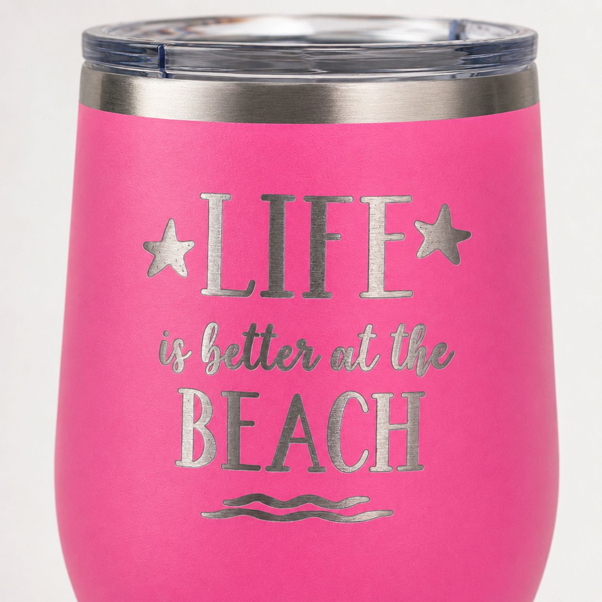 Close-up of pink beach tumbler with Life is Better at the Beach design