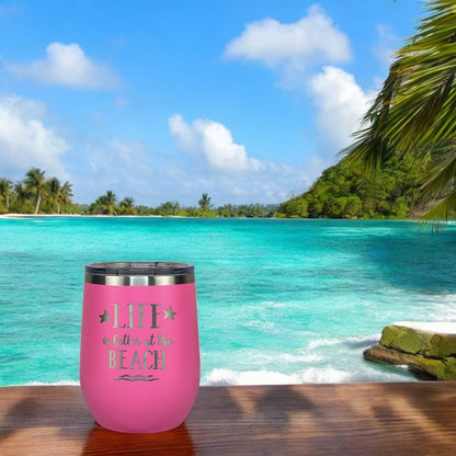 Pink tumbler with secure lid on a wooden table with ocean view, ideal for beach lovers