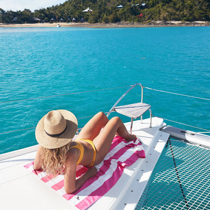 Pink striped microfiber beach towel draped over a woman on a boat during a beach vacation