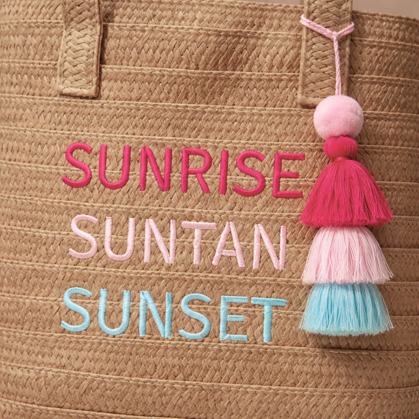 Close-up of Raffia Message Beach Bag Tote embroidery and tassel charm.