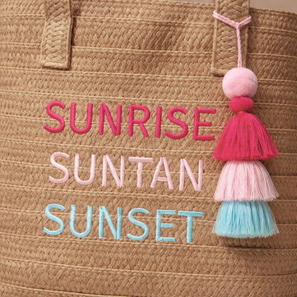 Close-up of Raffia Message Beach Bag Tote embroidery and tassel charm.