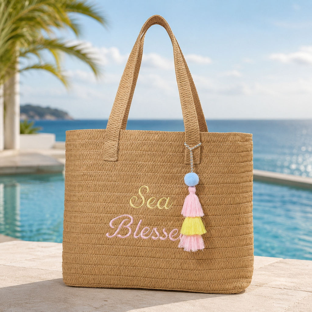 Sea Blessed raffia tote bag by a resort pool with an ocean view