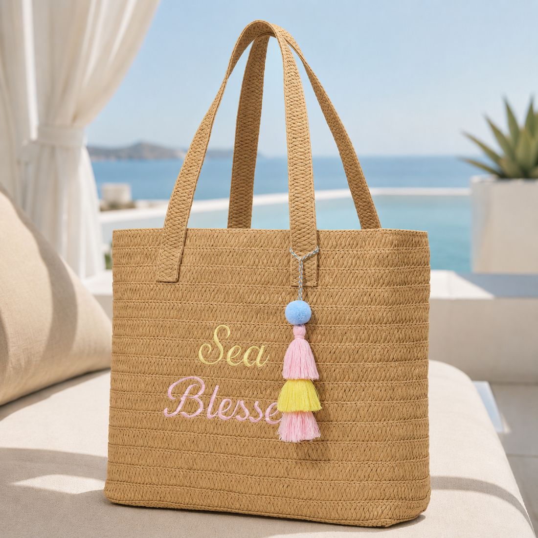 Sea Blessed raffia tote bag on a cream resort cabana seat with pool and ocean views