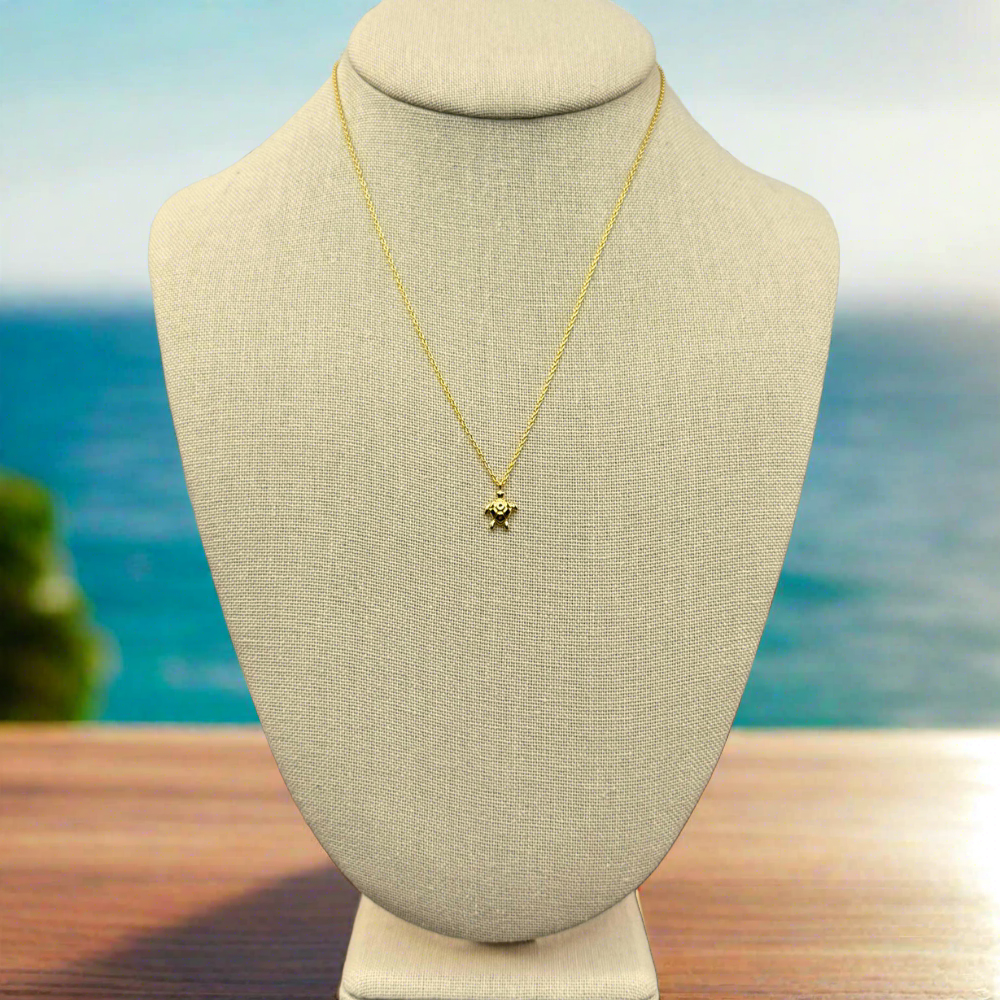 dainty, sea turtle pendant necklace 18k gold dipped necklace is perfect jewelry accessory for beach lovers on linen jewelry display with beach background