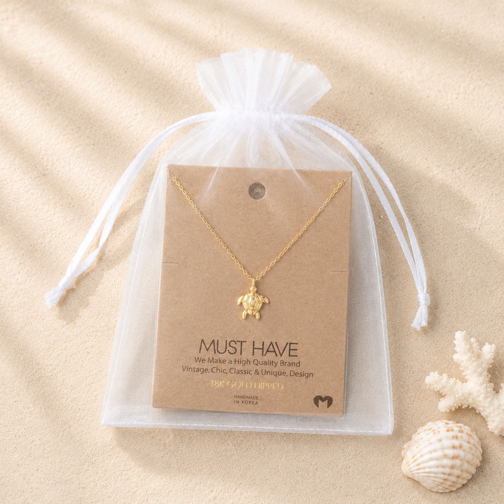 Gold sea turtle necklace packaged in a white organza bag, a gift-ready detail included in a beach lover gift set for women.
