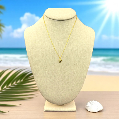 Sea turtle pendant necklace displayed on a linen jewelry bust with a single shell and palm leaf shadow, styled on a light surface with ocean views and a minimal beachy ambiance.