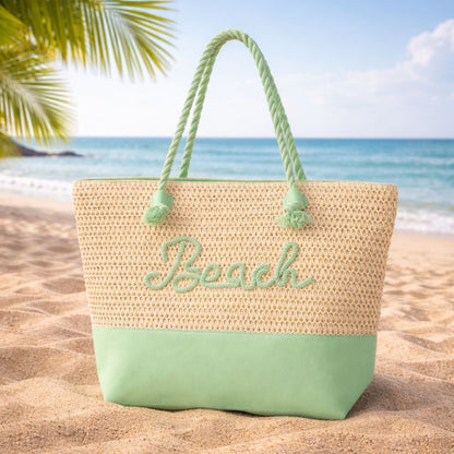 Mint green beach message straw tote bag on sand with ocean background