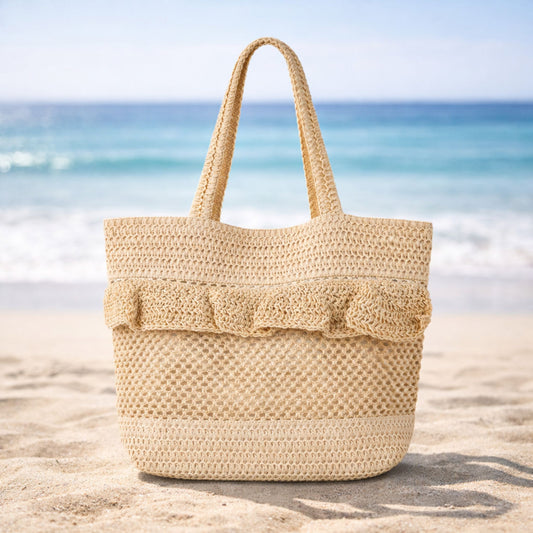 Beige crochet beach bag on sand at the beach.