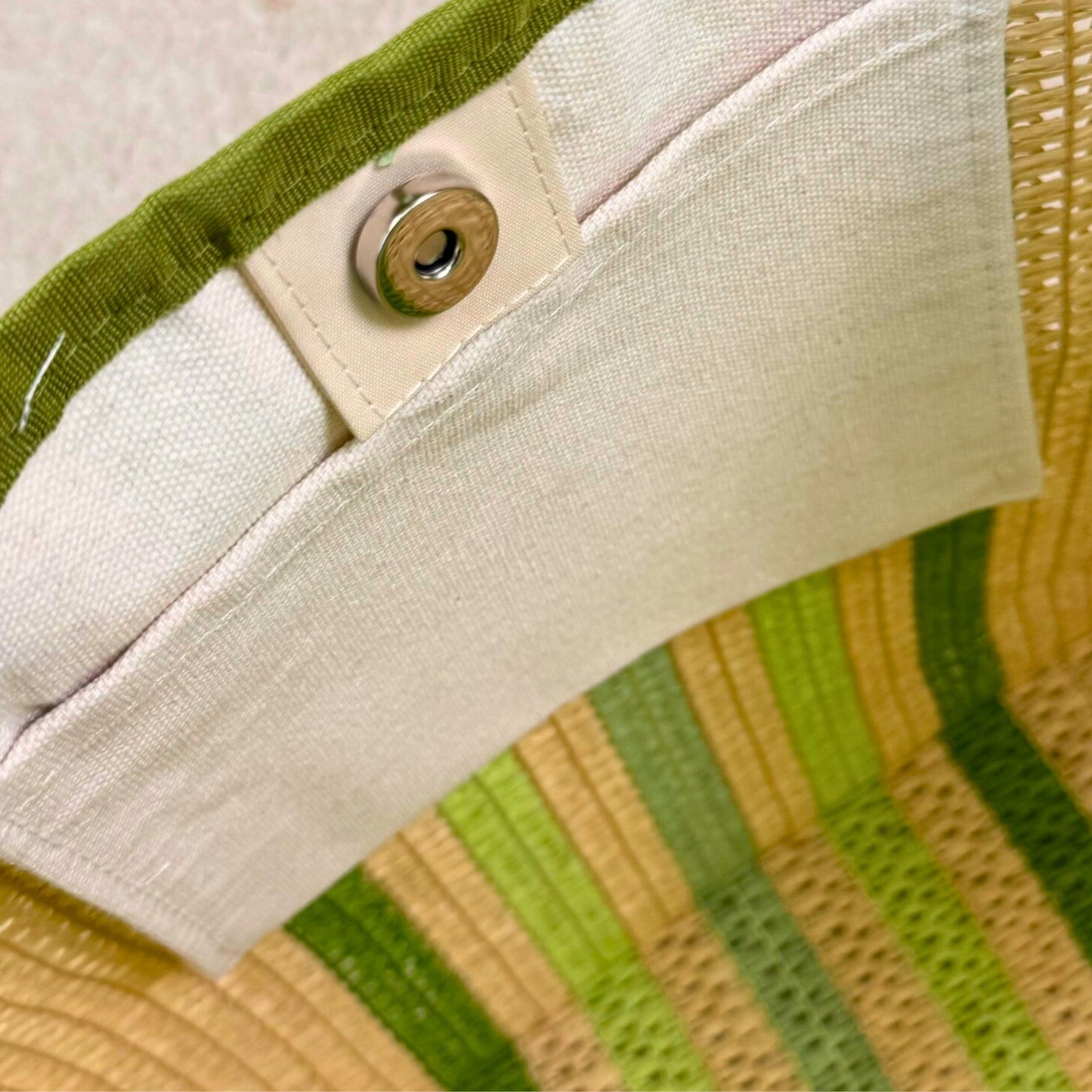 close-up of inside pocket with magnetic closure of a green striped straw beach bag tote