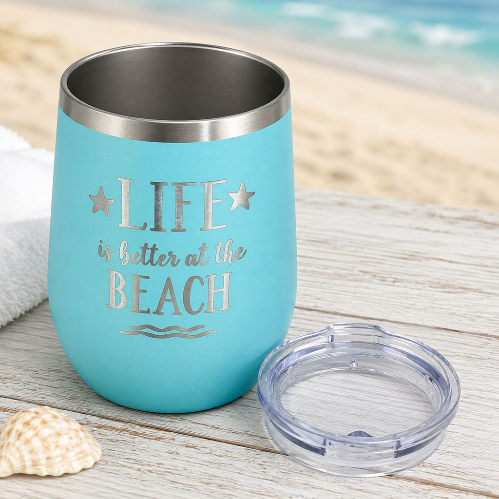 Teal beach insulated wine tumbler with clear lid on a coastal wood surface