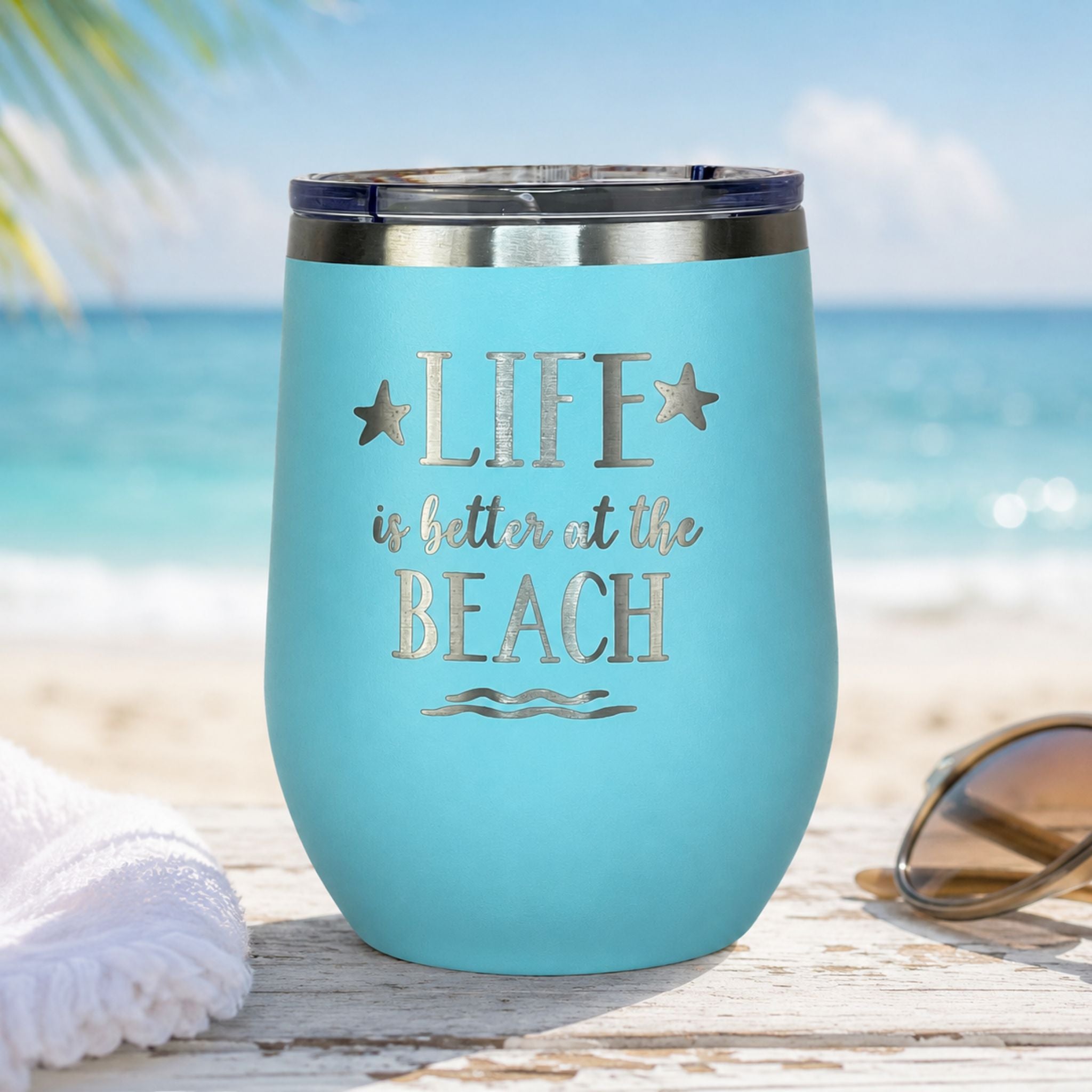 Teal beach insulated wine tumbler with lid on a coastal surface with an ocean beach background