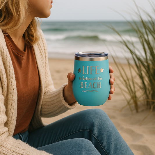 woman holding teal Life is Better at the Beach tumbler with wine at sunset