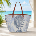Tropical leaf patterned tote bag with brown handles on a beach setting