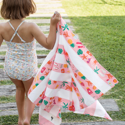 girl holding a pink striped beach pattern, quick dry, sand free kids beach towel